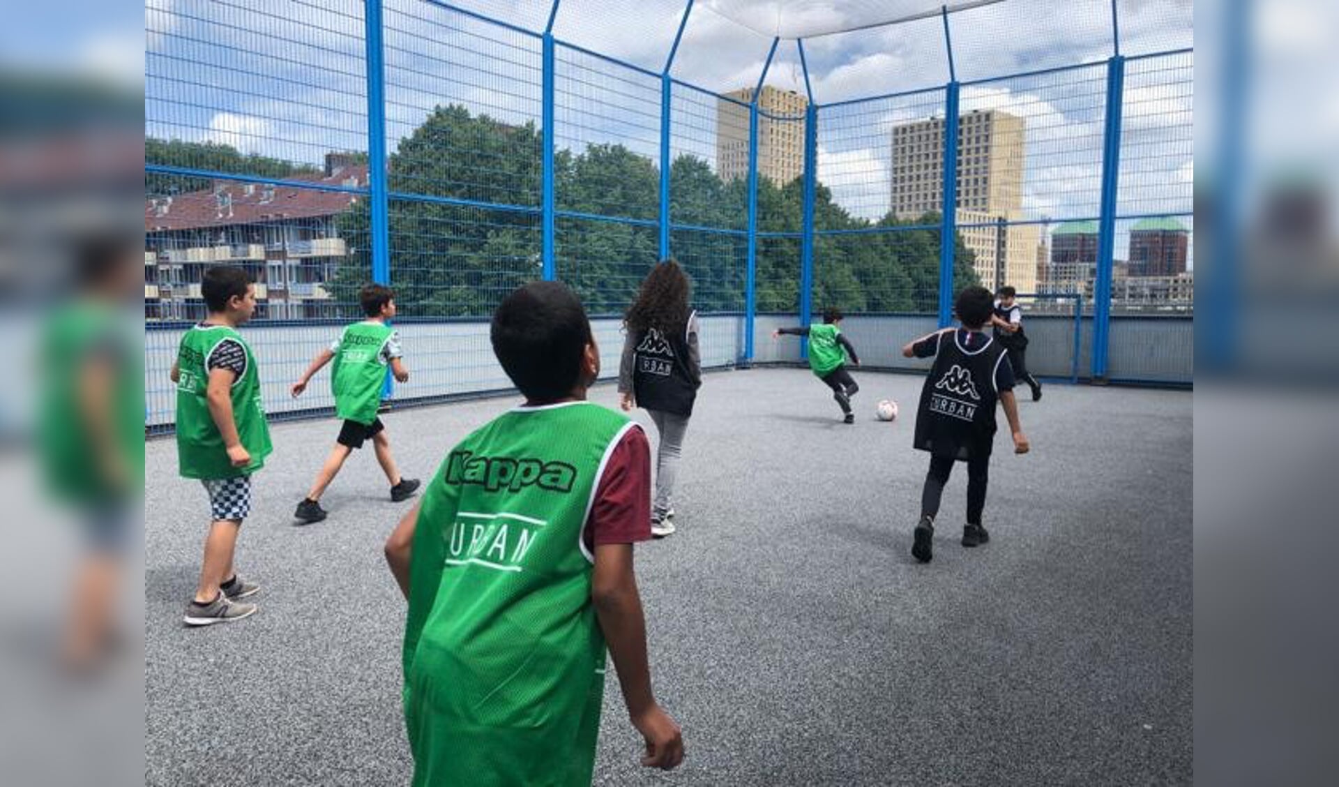 Jongens en meisjes voetballen op het schoolplein van het Calvijn College in Amsterdam West.