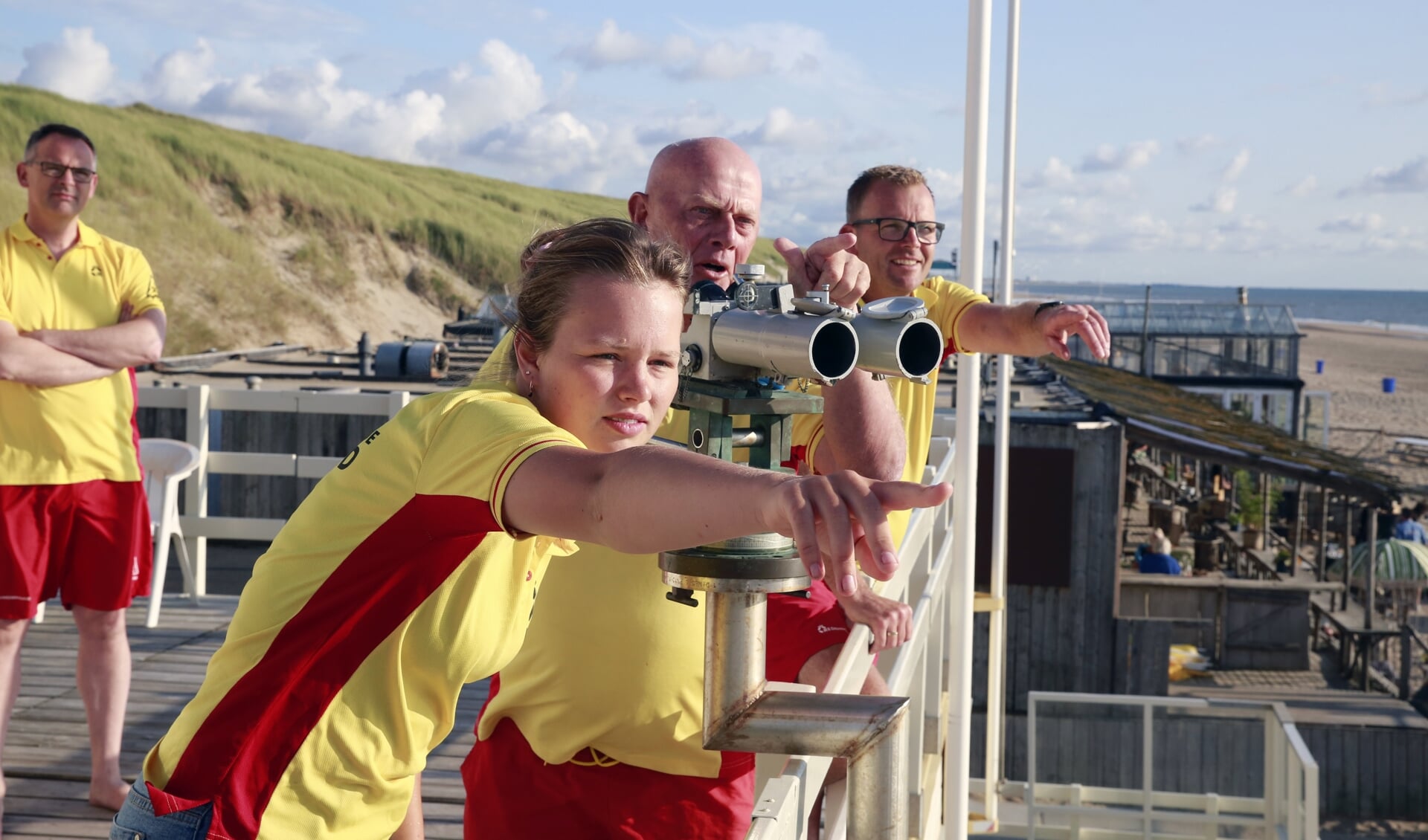 Commandant Harrie Hamakers (achter de verrekijker) en de andere lifeguards van Reddingsbrigade Castricum op hun post. Ze wijzen  naar de muien in zee.