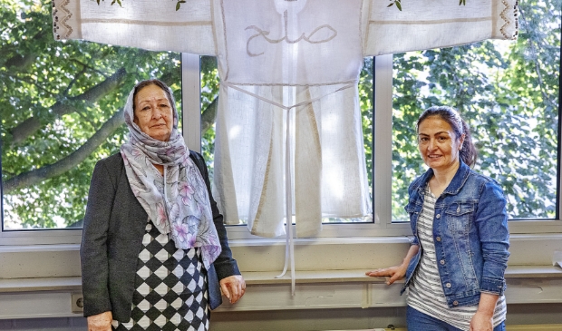 <p>Nasima en Zakya bij de traditionele Afghaanse jas die zij in het kader van de Vredesweek maakten. Op de jas is in het Dari, een van de officiële talen in Afghanistan, het woord voor 'vrede' geborduurd.</p>