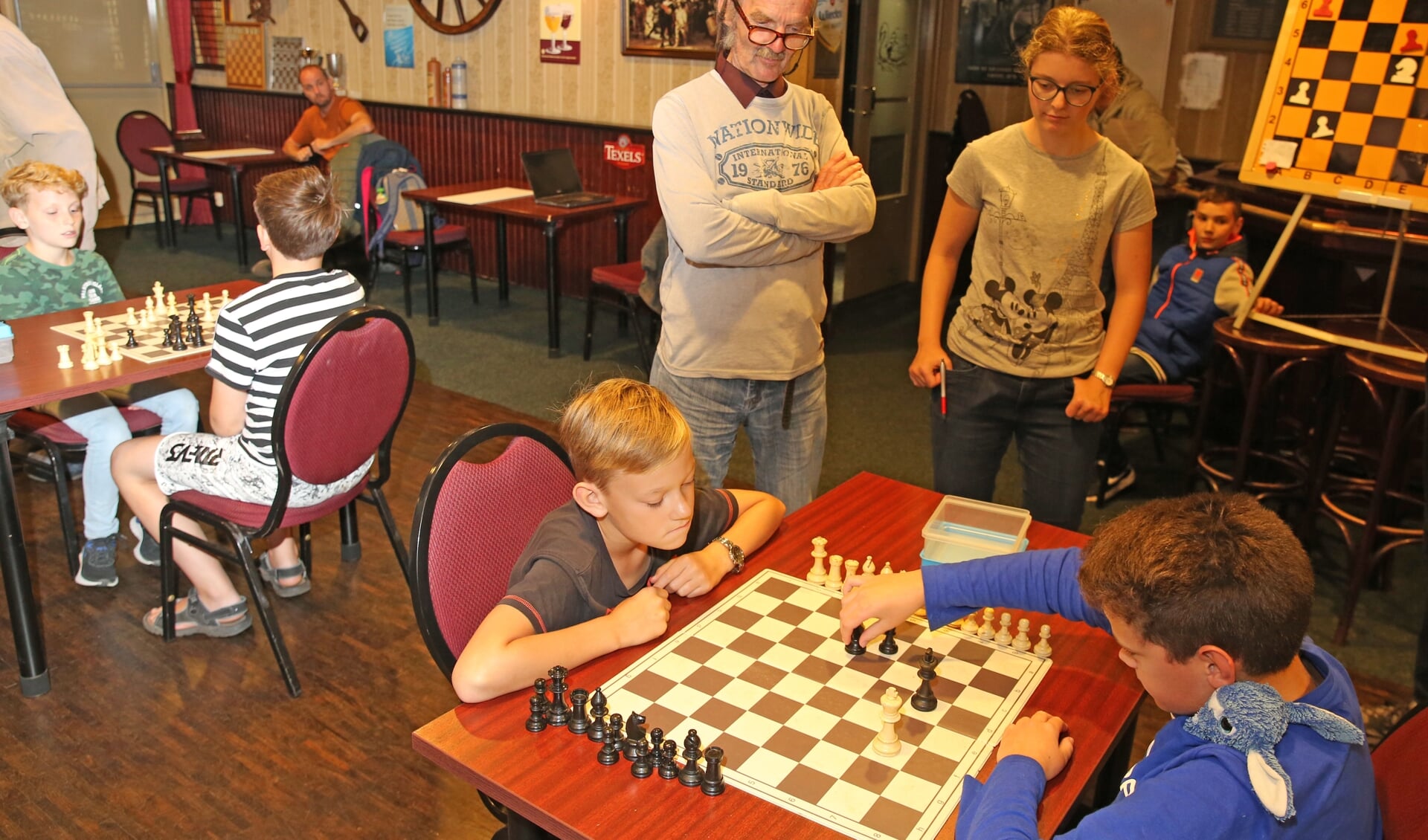Piet Konijn (staande midden met bril) kijkt met voldoening naar de jeugdschakers.