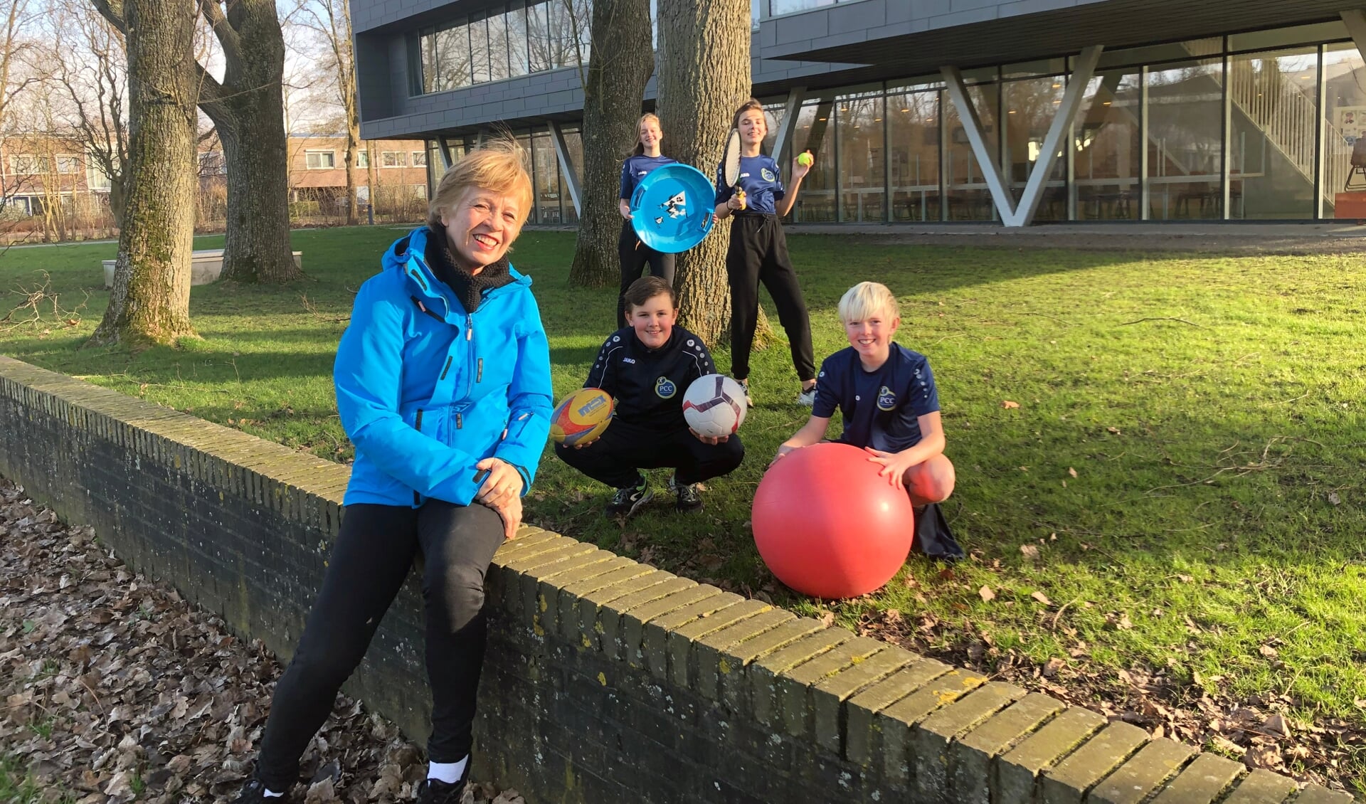 Astrid Langedijk met - op vereiste covid-afstand - vier van haar laatste generatie sportklasleerlingen uit de brugklas op PCC Heiloo: de dertienjarige Feline (met ronde slee) en Noortje (met racket) uit Heiloo, en Willem (voetbal) en Bram (skippybal) uit Alkmaar.