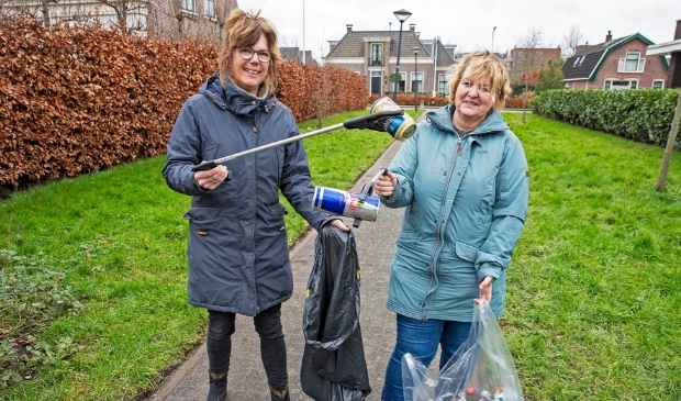 <p>Sandra (l) en Linda ruimen met een prikstok afval op van de straat. "We hopen mensen wakker te schudden en aan te sporen om ook iets te doen."</p>