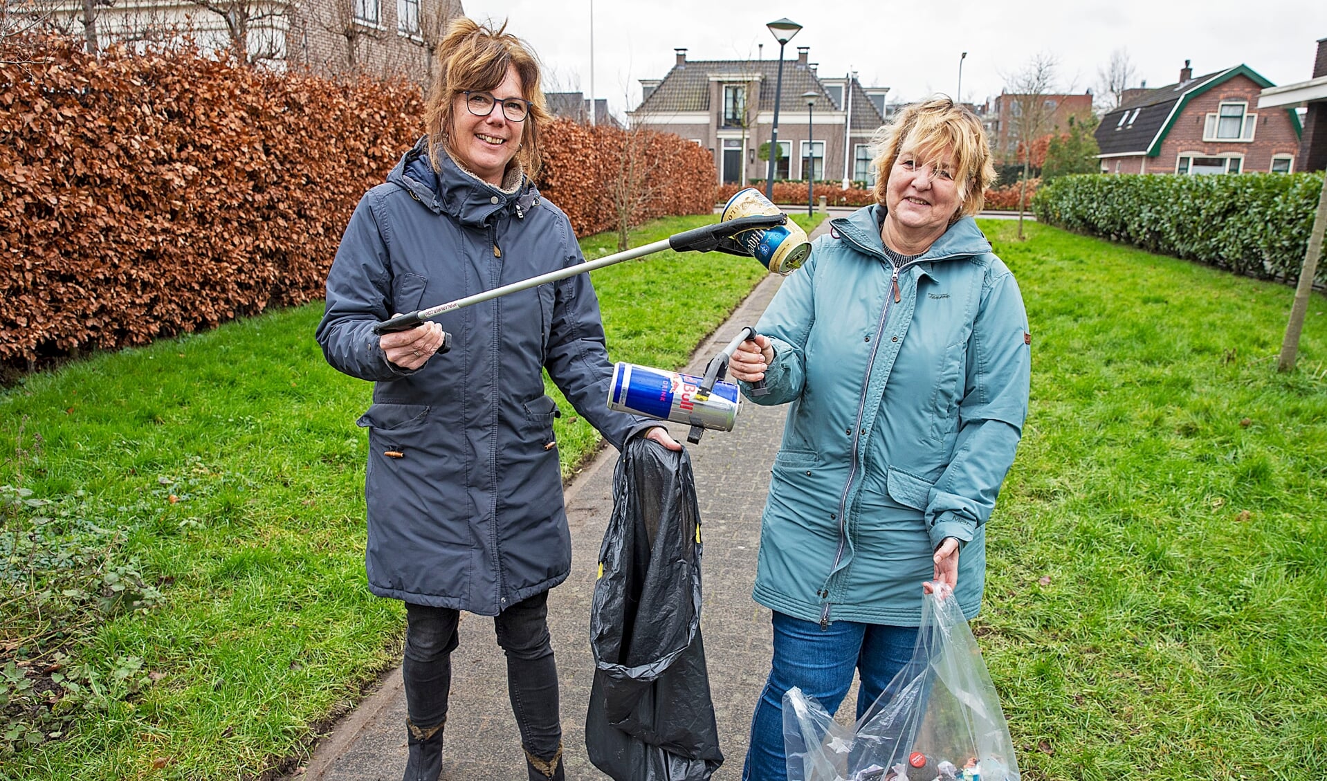Sandra (l) en Linda ruimen met een prikstok afval op van de straat. "We hopen mensen wakker te schudden en aan te sporen om ook iets te doen."