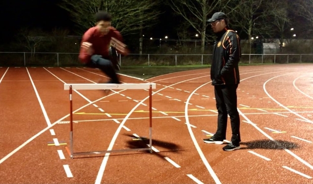<p>Robin Korving (r) traint in de avonduren talentvolle hordelopers op de atletiekbaan van Hera.</p>