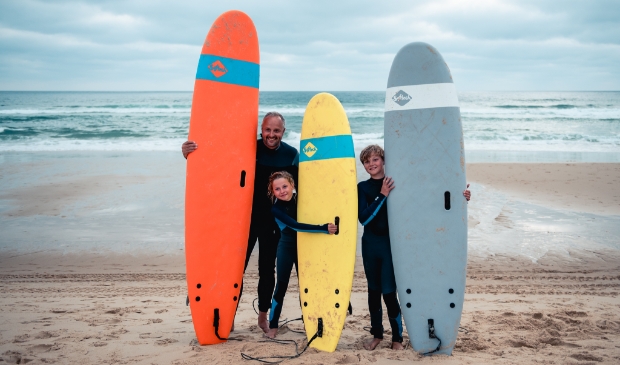 <p>Vader met zijn kinderen surfen op het strand van Bloemendaal.</p>