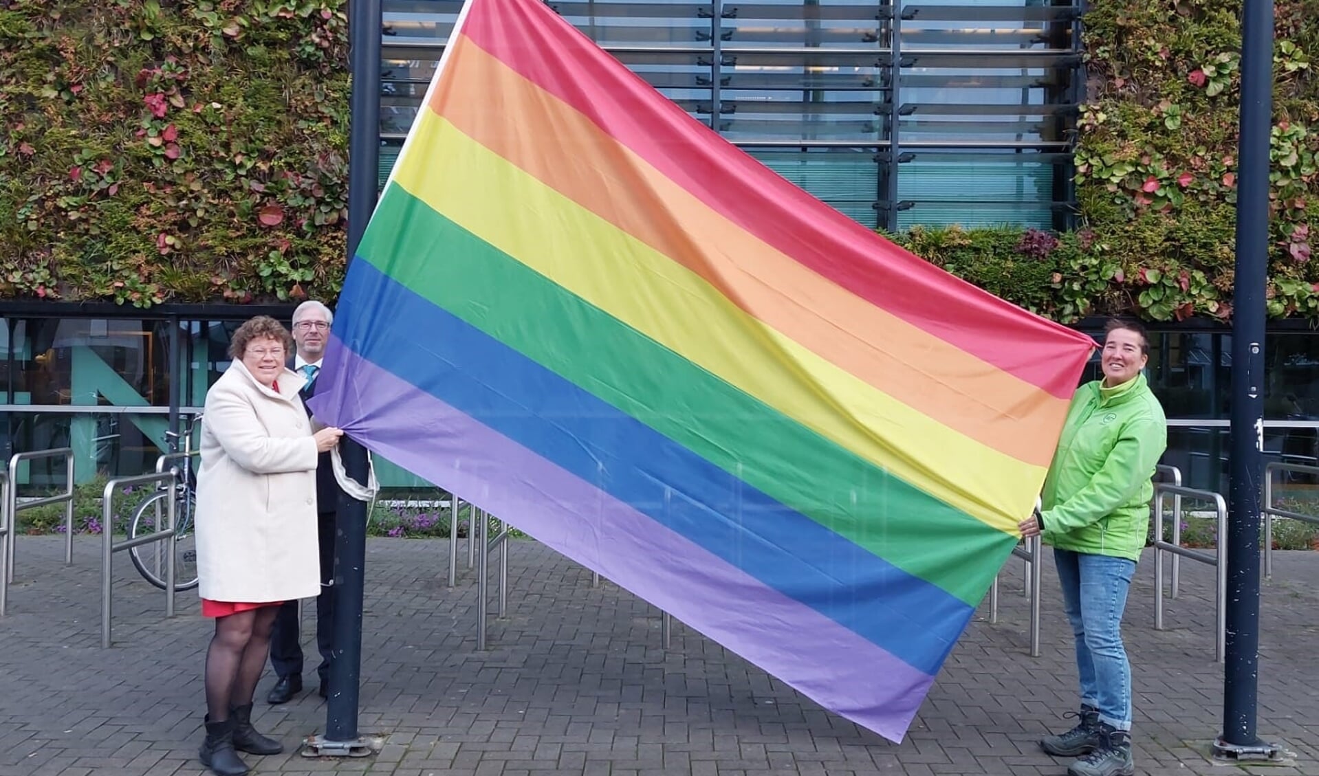 Wethouder Annette Groot (l) en aandachtsfunctionaris LHBTI van MET Welzijn Suleika van Holland (r) hesen de regenboogvlag.