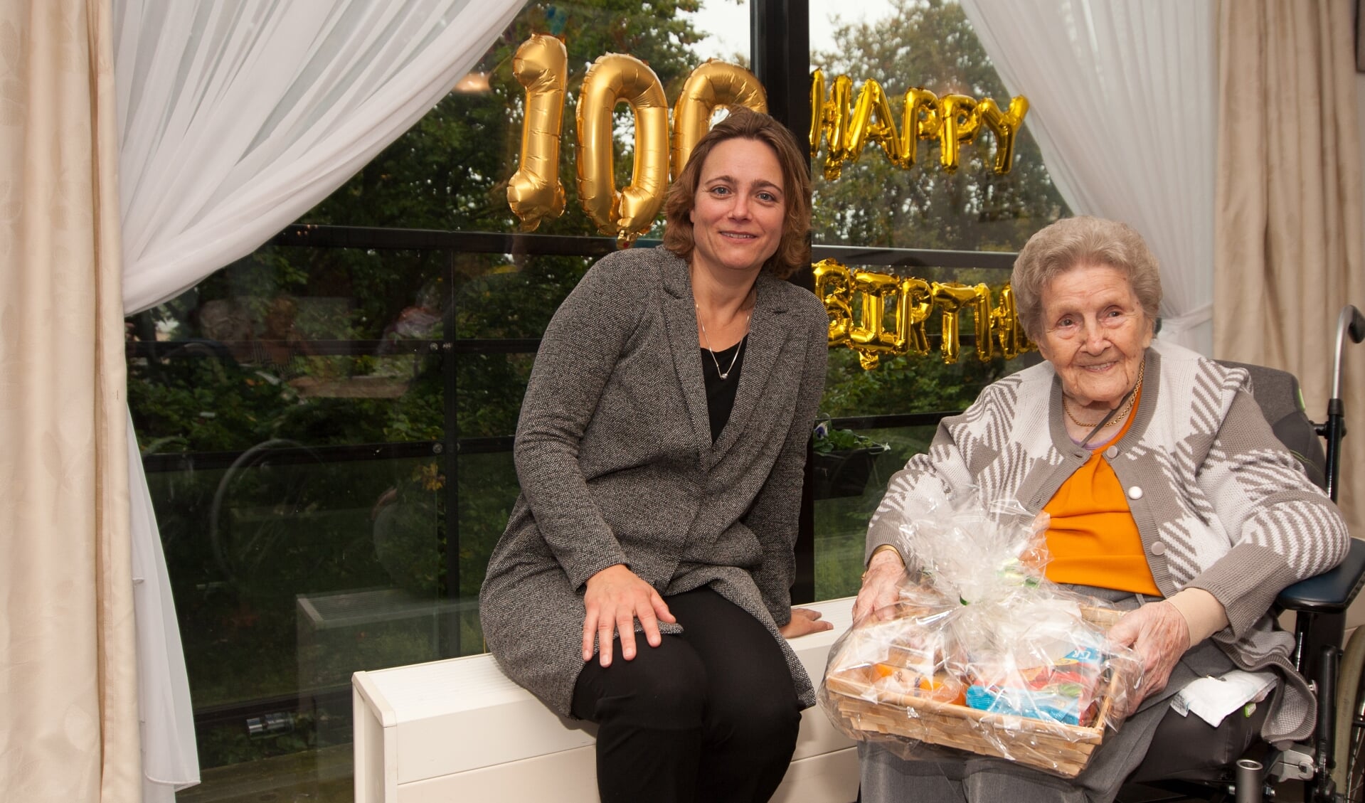 Mevrouw van Wageningen ontvangt op haar 100e verjaardag bezoek van stadsdeelvoorzitter Erna Berends. 