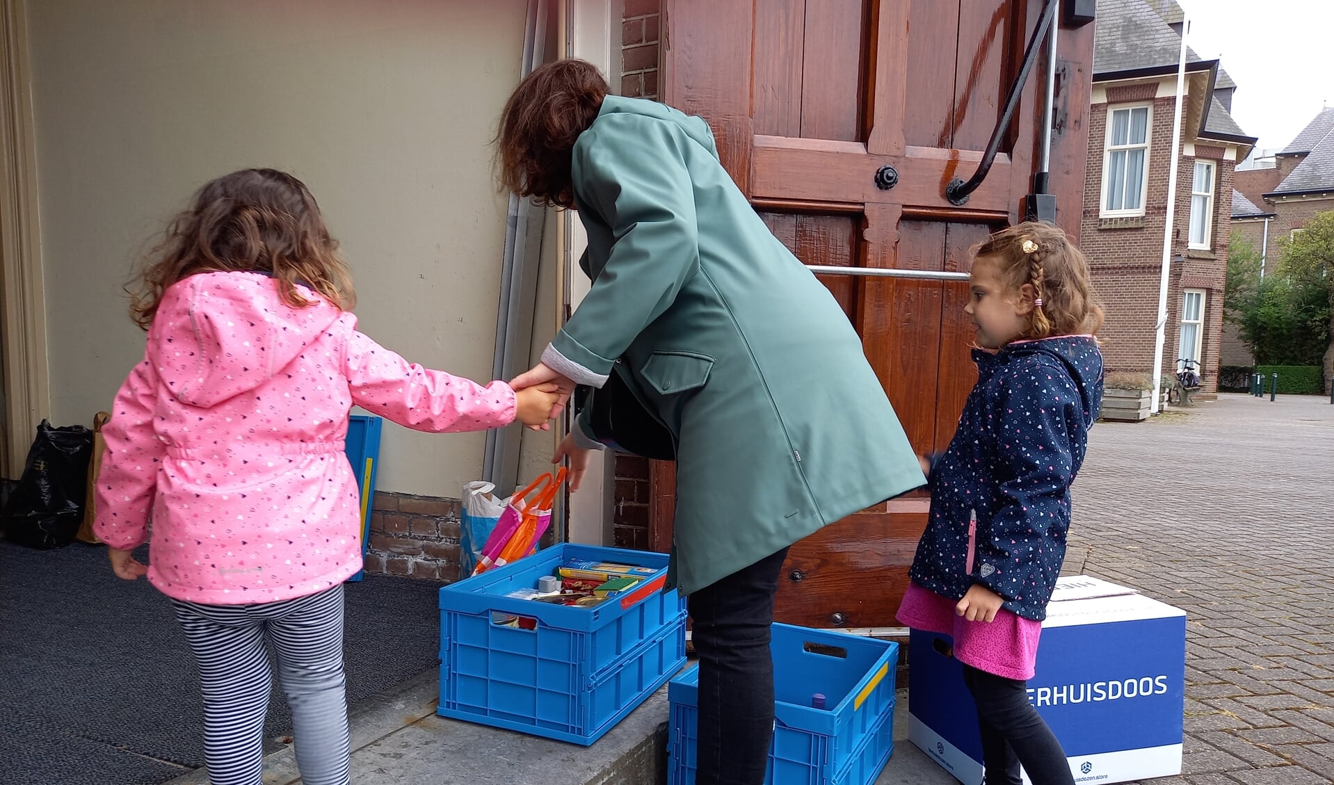 gezin brengt levensmiddelen voor de Voedselbank bij de Pancratiuskerk.
