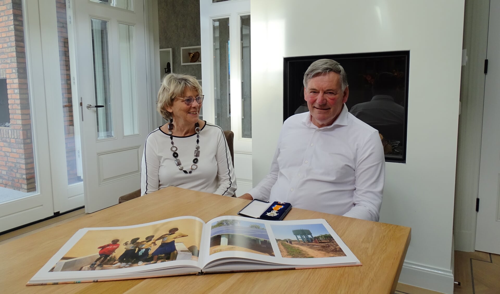 Het echtpaar op de foto met het lintje en een fotoboek over Lamin.