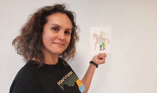 <p>Wil je een giclee winnen van het werk met de ridder, de prinses en het paard, dat Hanna op deze foto in haar hand houdt? Doe mee met de winactie</p>