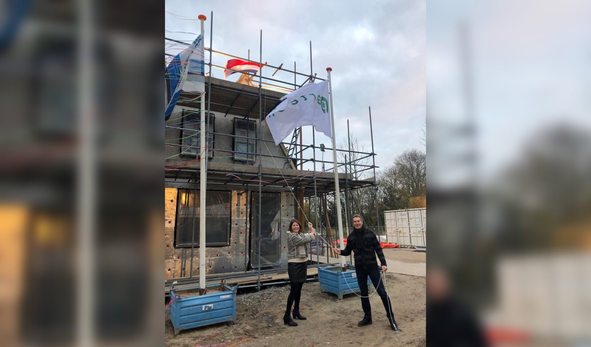 Monique Kwaak (manager Vastgoed Parteon) en Levinus Jongmans (programmamanager gemeente Zaanstad) hijsen de vlag. 