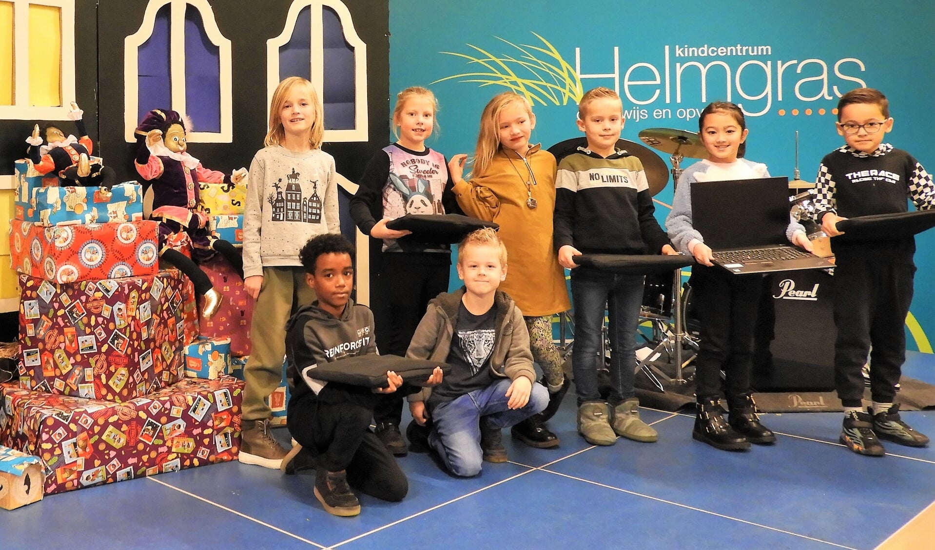 Leerlingen van Kindcentrum Helmgras nemen de eerste vijf laptops in ontvangst die gedoneerd worden aan kinderen die ze goed kunnen gebruiken. 