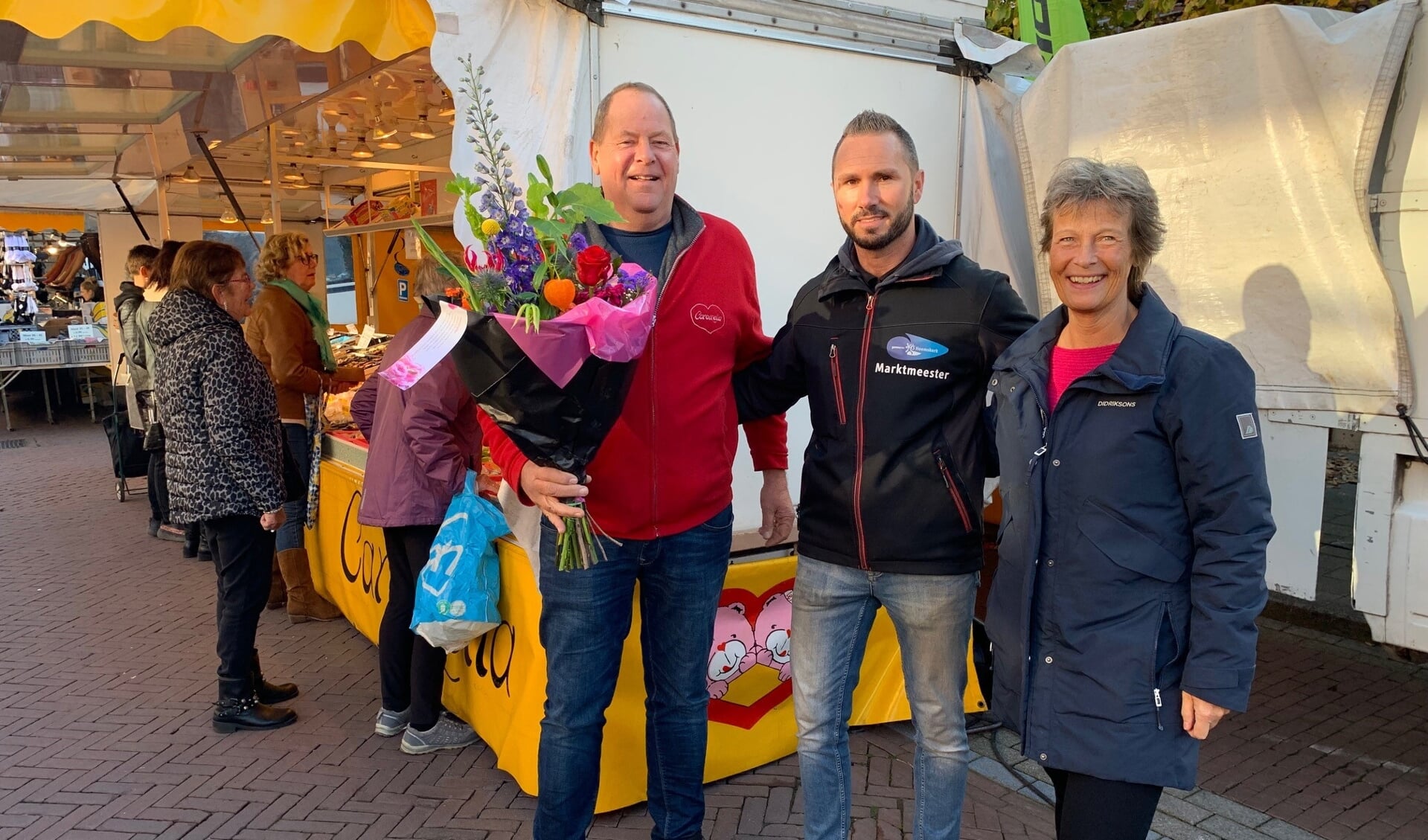Marktkoopman Chris Newsky (links) met marktmeester Erik de Vrij (midden) en Chris' partner Ingrid.