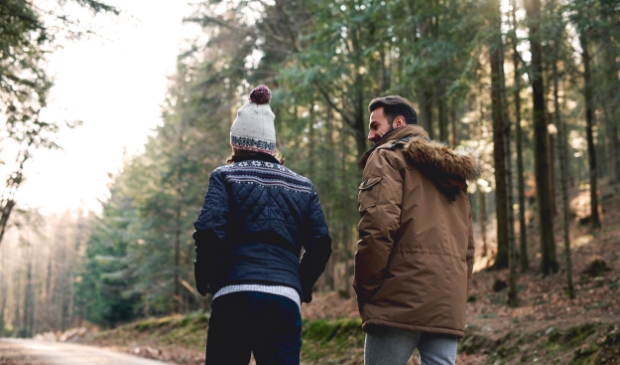 Rear view of father and son walking in autumn forest
