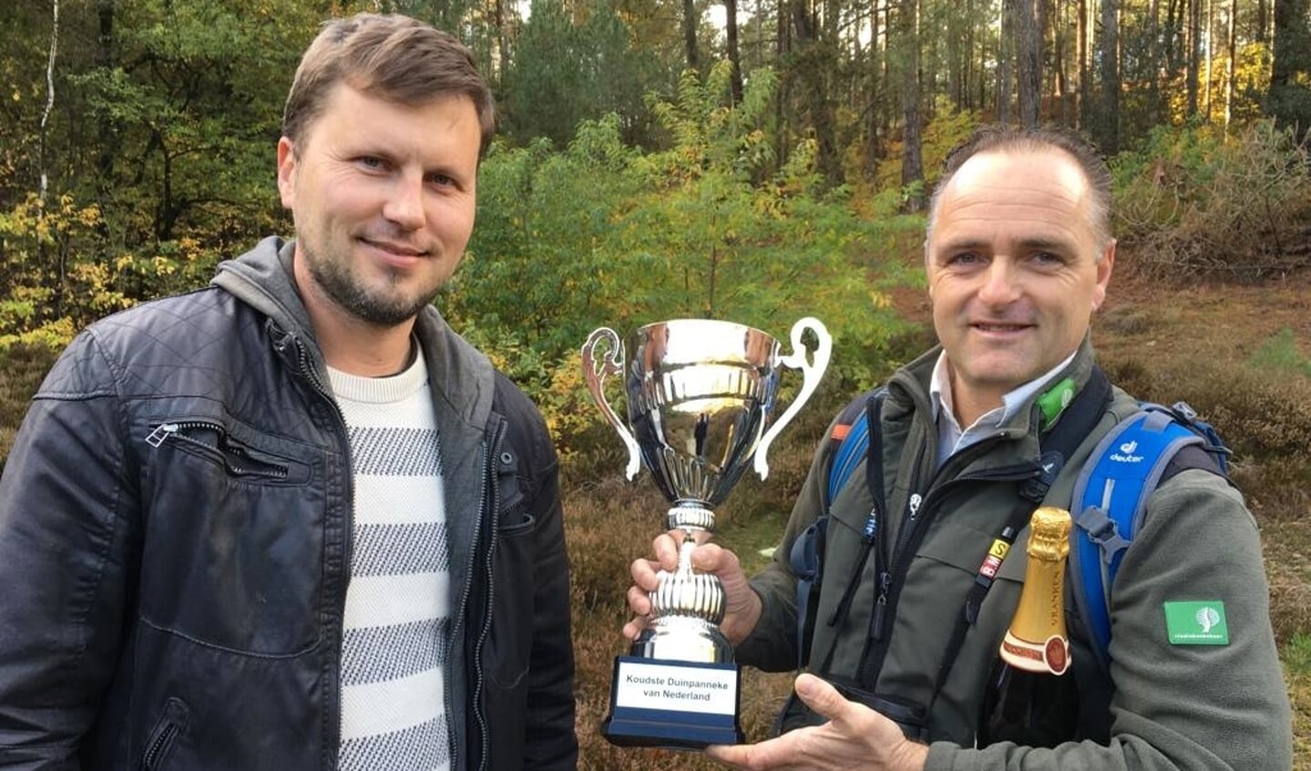 Boswachter Leon Kelder (rechts) neemt de trofee voor het ‘Koudste Duinpanneke van Nederland’ in ontvangst.
