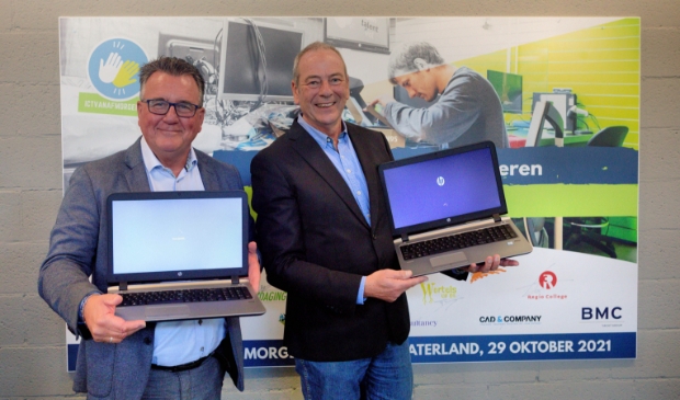 <p>Wethouder Stadspartij Purmerend Mario Hegger (links) en Nico Braam, voorzitter Zaanse Uitdaging, tonen de eerste refurbished laptops bij de opening van ICT vanaf Morgen voor de Zaanse en Purmerendse jongeren. </p>