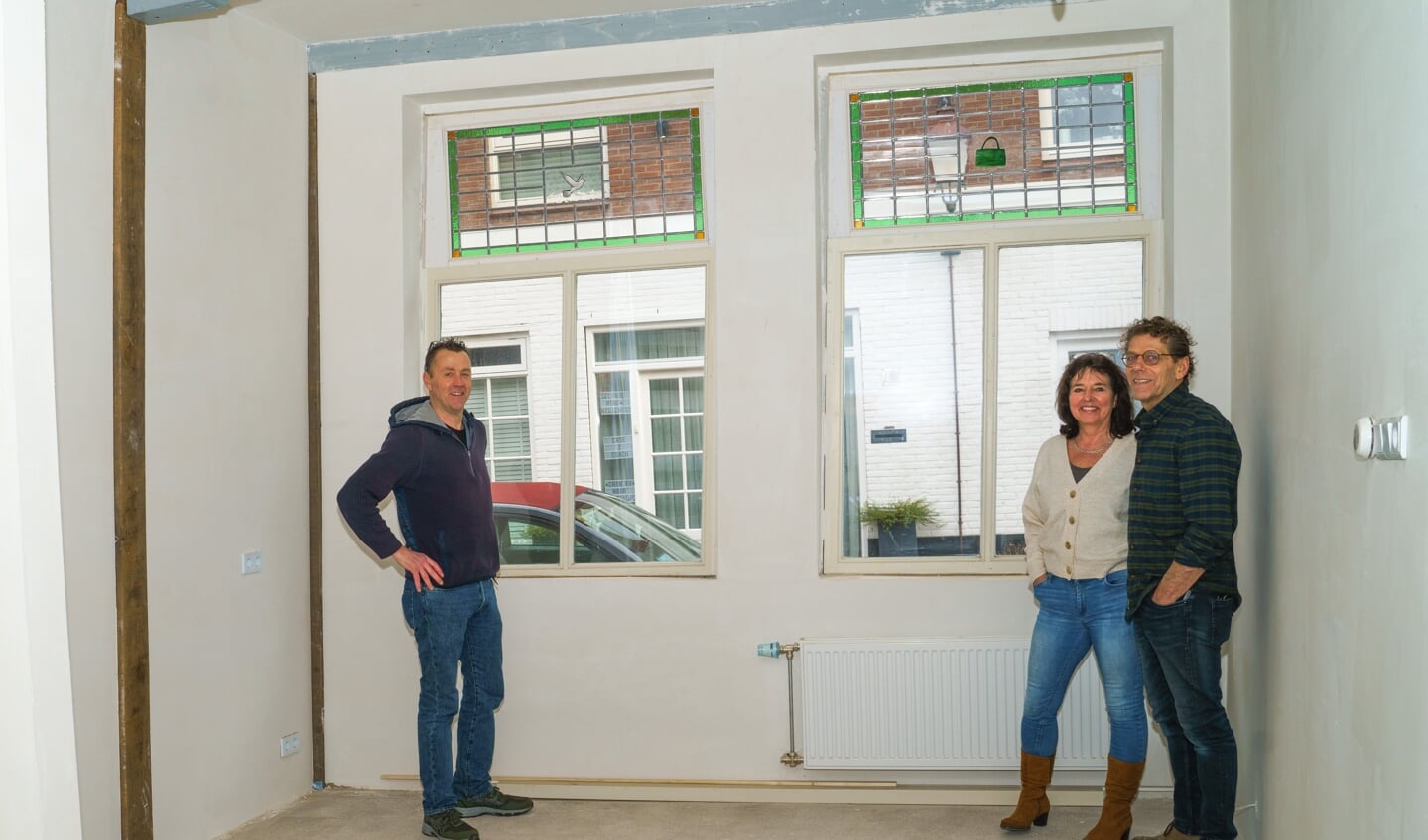 Ruud Harberts, Elsa de Zwart en Gerard van Parreeren bij de nieuwe glas-in-loodramen in het huis aan de Gravenstraat. n het ene raam prijkt een witte duif, in het andere raam een groen tasje.