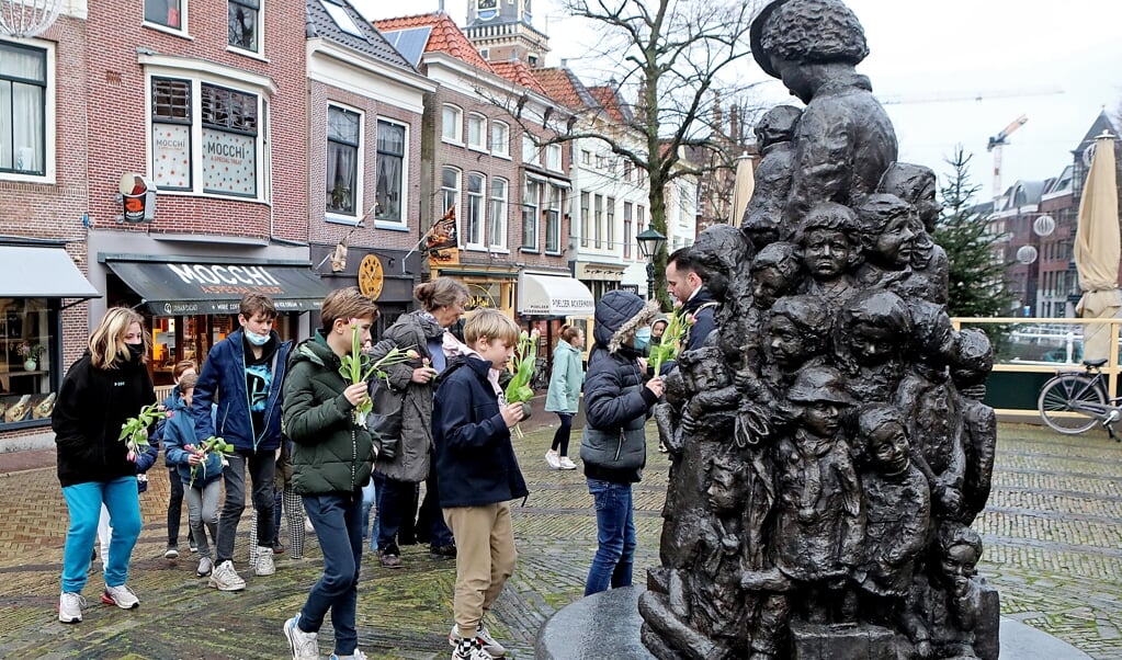 Leerlingen uit groep 8 van basisschool Kennemerpoort leggen bloemen bij het beeld van Truus Wijsmuller.