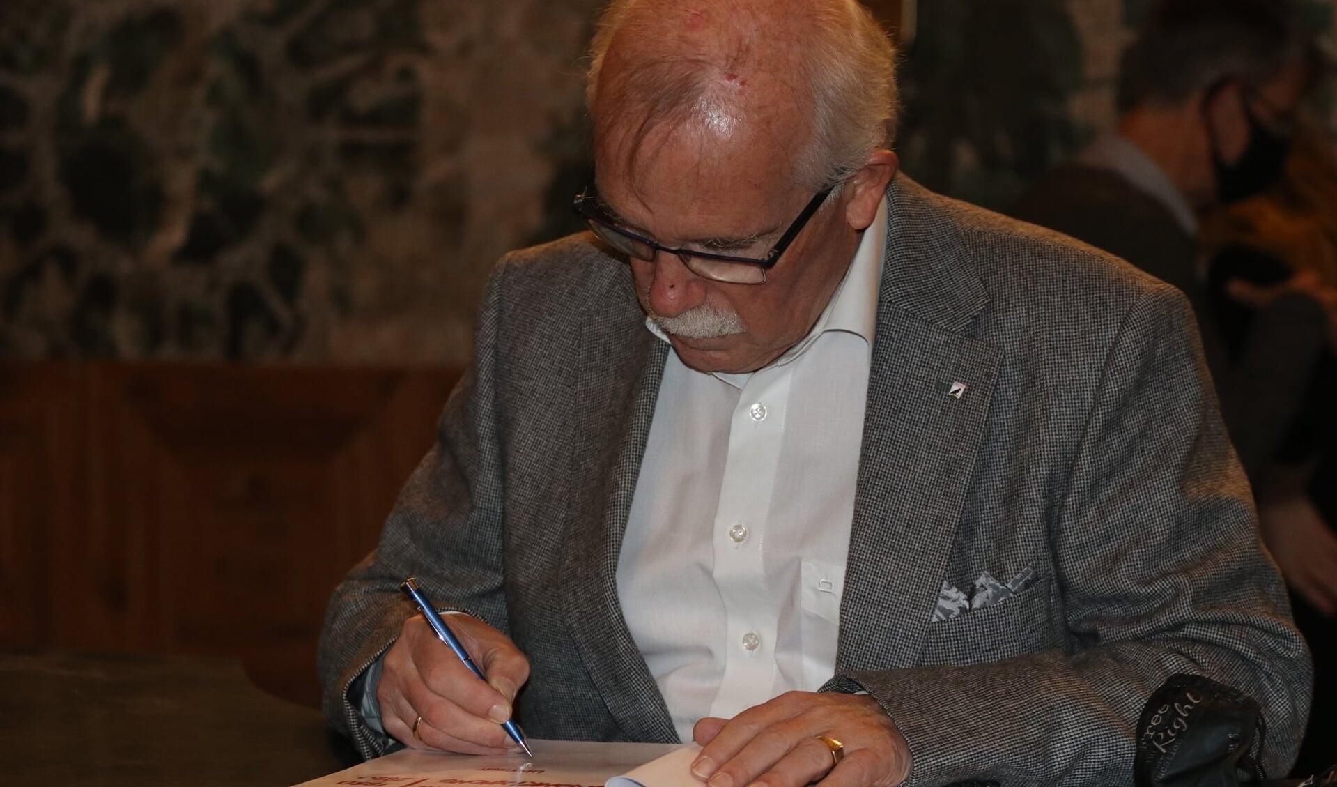 Auteur Wim Spruit zet zijn handtekening in het boek.
