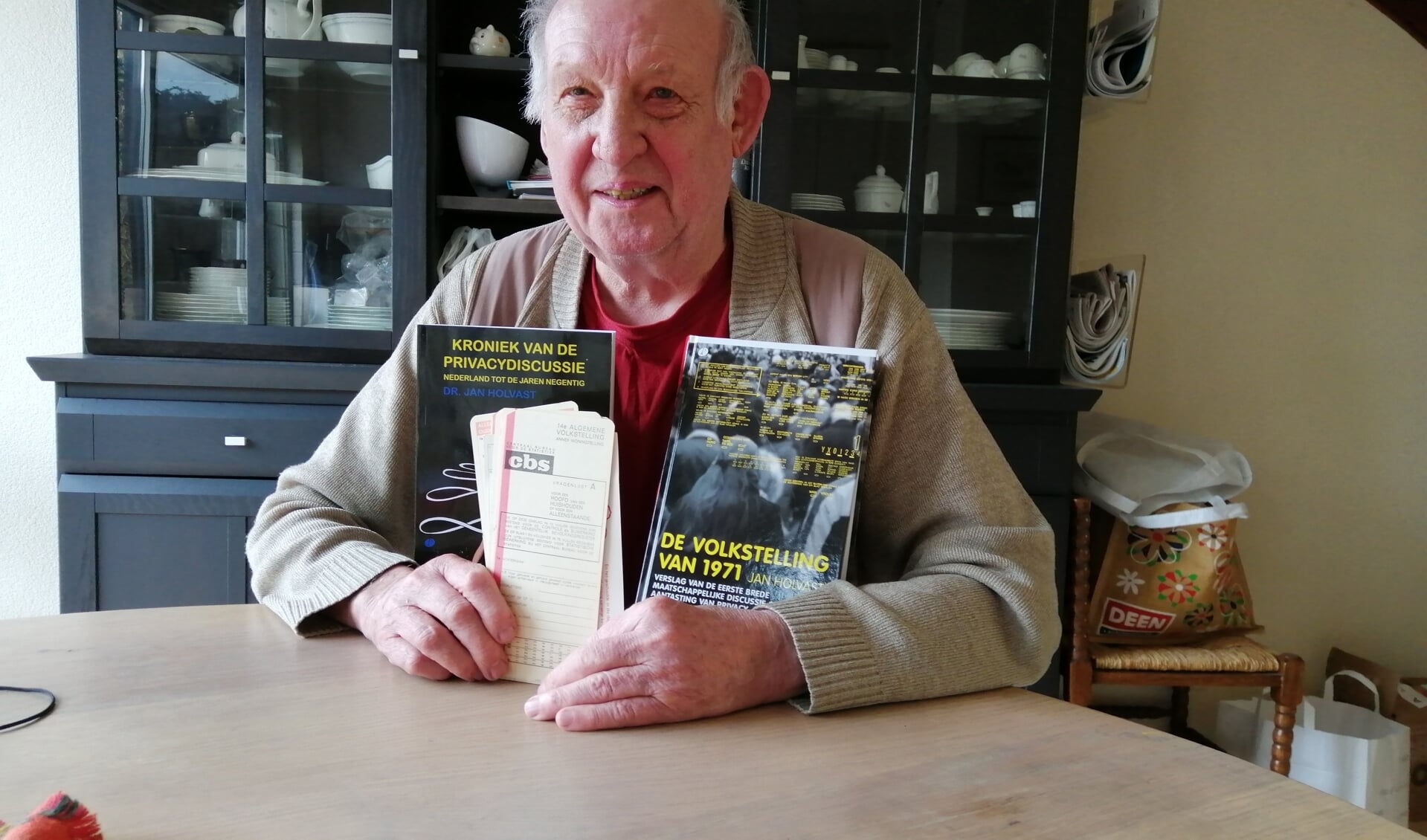 Jan Holvast met twee van zijn boeken en een aantal ponskaarten, die vijftig jaar geleden werden gebruikt voor het vastleggen van persoonsgegevens.