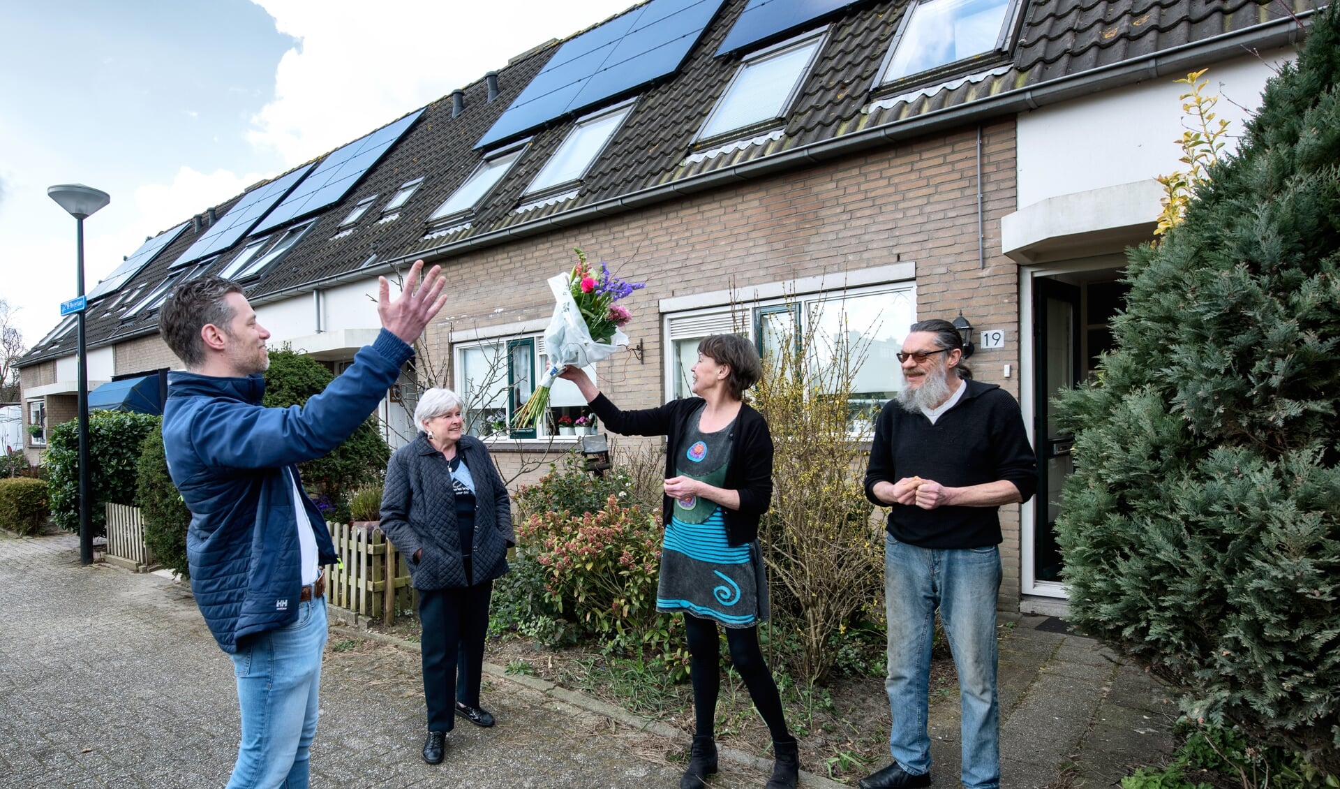 Bewoners ontvangen een bloemetje om te vieren dat de Jacob de Weijerlaan 100% gaat voor zonne-energie.