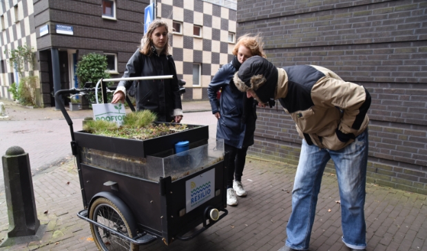 <p>Buurtbewoner van het Noorderhof bekijkt bij de dakfiets hoe het allemaal werkt. </p>