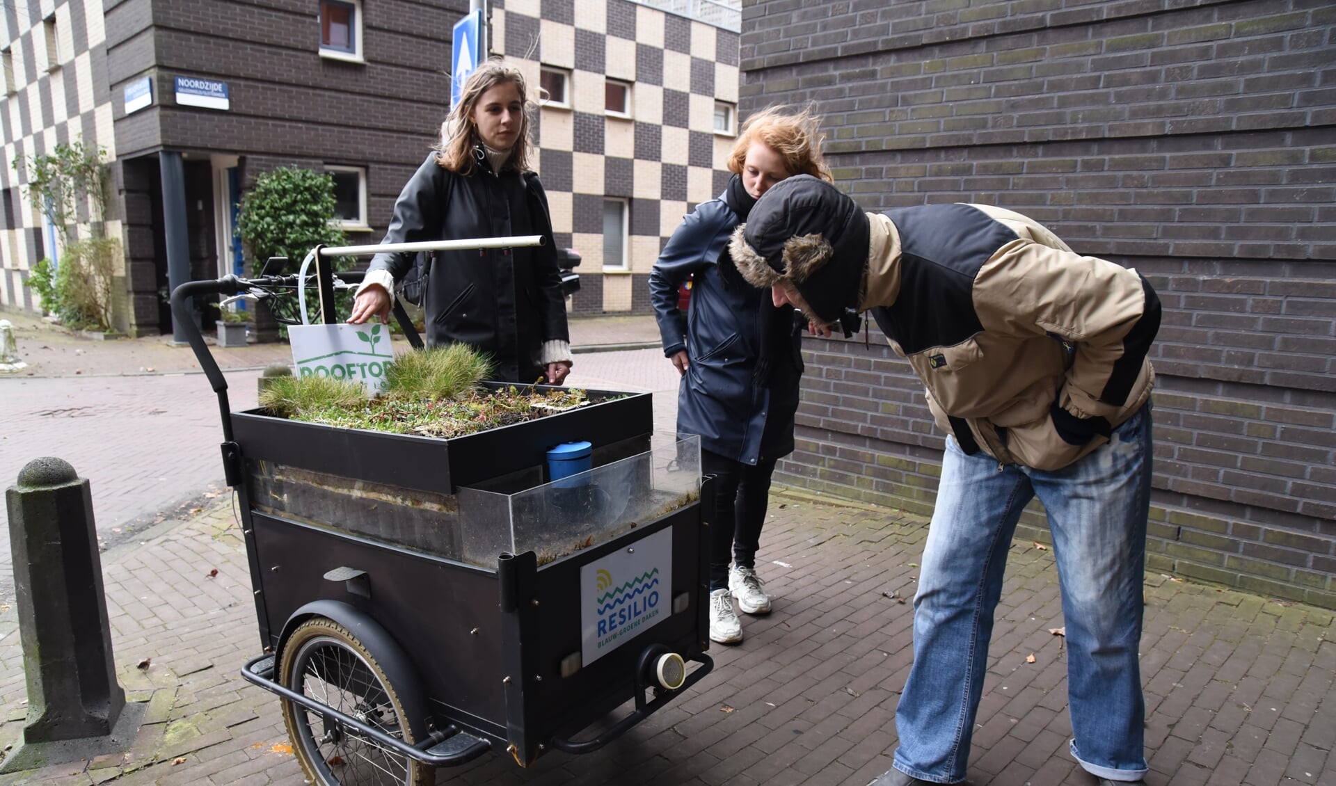 Buurtbewoner van het Noorderhof bekijkt bij de dakfiets hoe het allemaal werkt. 