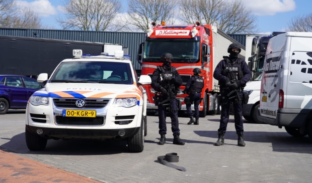 <p>Zwaarbewapende agenten houden de wacht bij een bedrijfspand aan de Lorentzstraat.</p>