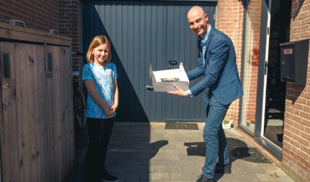 <p>Wethouder Robert Tesselaar reikt fototaart uit aan Maud Maas.</p>