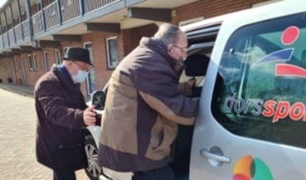 <p>Gerard Webbers wordt door vrijwilliger Jan Vink in de auto geholpen.</p>