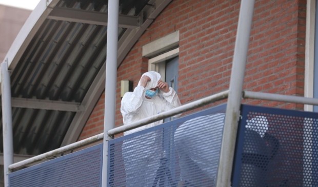 <p>Mannen in witte pakken voeren onderzoek uit bij de woning.</p>