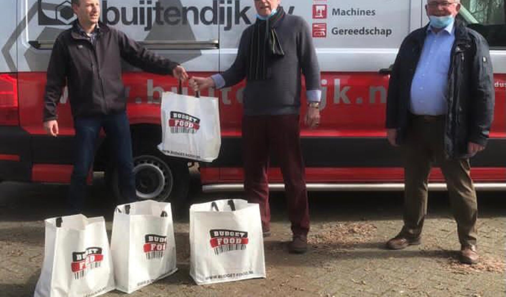 Edwin Wilms en Willem Fritzemeijer van Rotary Club Den Helder overhandigen de pakketten symbolisch aan Nico Bais, voorzitter van de Helderse Voedselbank.