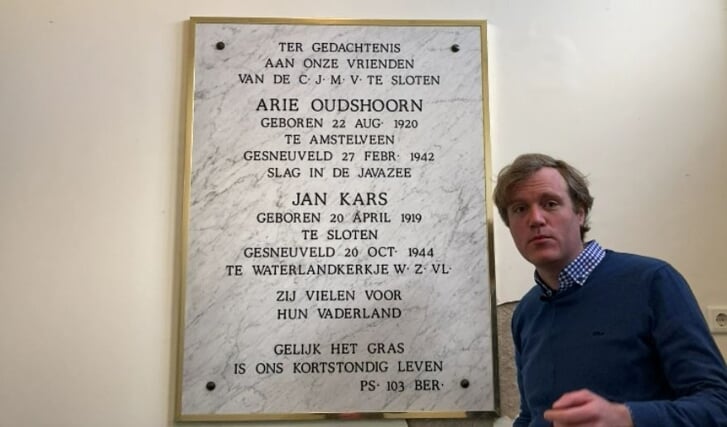 Dominee Martijn van Leerdam bij de plaquette in de Sloterkerk.
