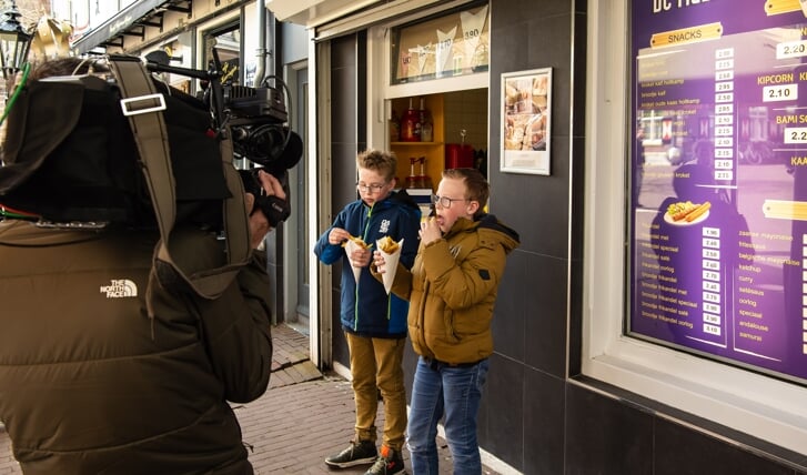 Jasper (links) en Niels de Kraker genieten onder de opnames van het Jeugdjournaal van een heerlijk patatje mét van de Mazzel. 