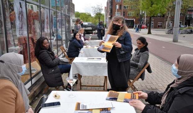 <p>Fiona de Bell reikt de gebundelde verhalen en foto’s uit aan de ondernemers en Westerpost.</p>