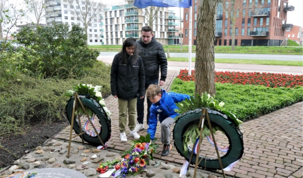 <p>Sven Lekic en Kim Broekhuijsen van Trifolium leggen bloemen bij het monument aan de Jaagweg. Achter hen meester Dennis.</p>