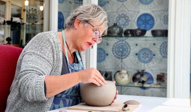 <p>Keramiste Gerdien Noordeloos in haar atelier waar zij werkt aan een urn.</p>