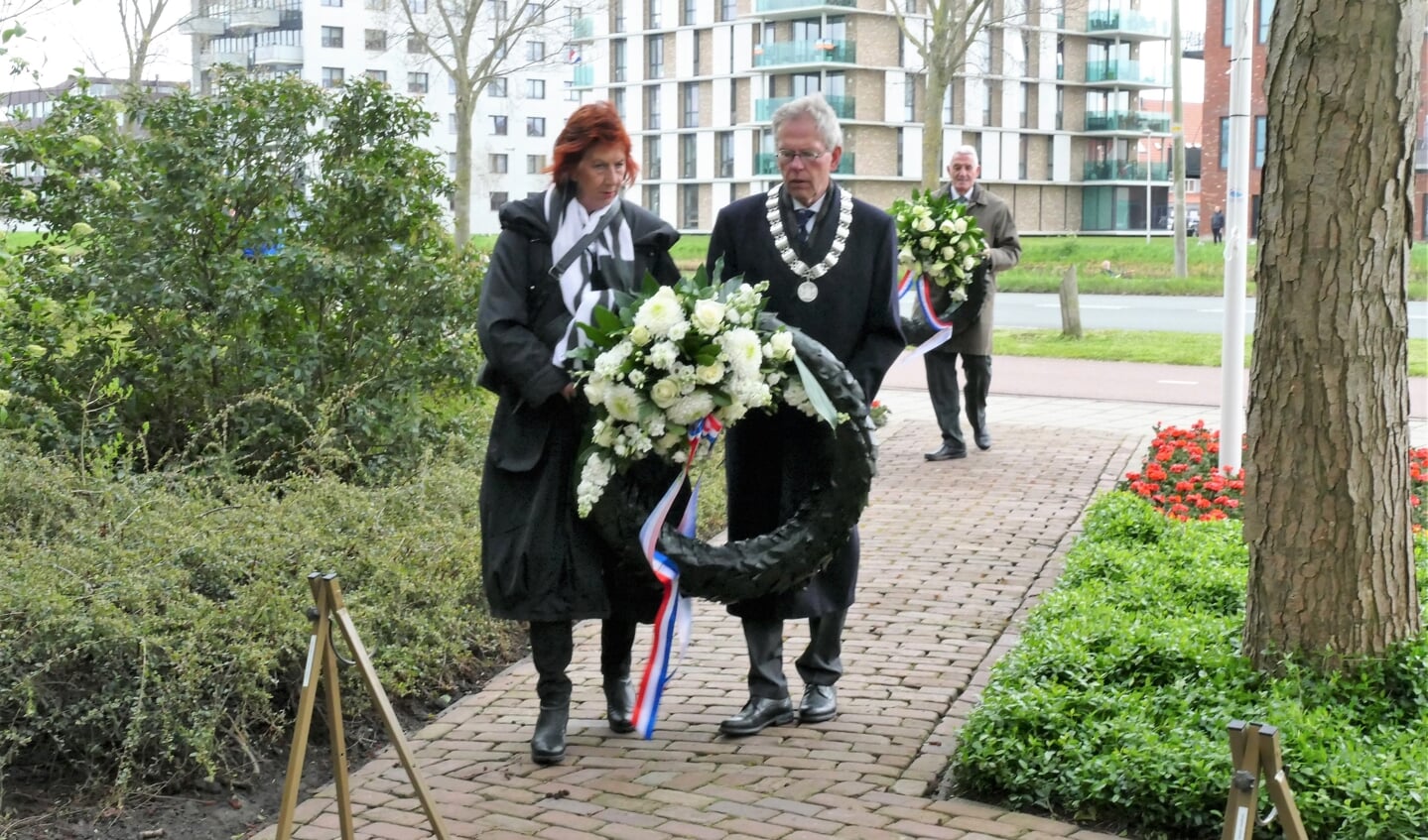 Burgemeester Don Bijl en zijn echtgenote met een krans op weg naar het monument aan de Jaagweg.