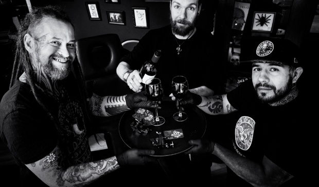 <p>Tatoeëerders Marc Forster en Luis Schaft helpen caféhouder Sjoerd Beekes met een tattoo flash dag/veiling. </p>