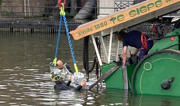 <p>Met man en macht wordt de stoomwals uit het water getakeld.</p>