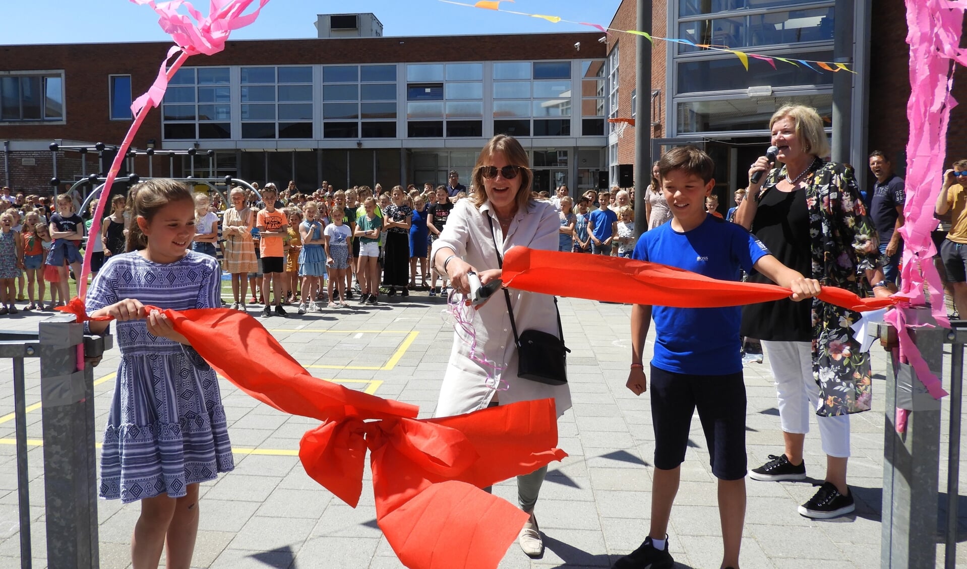 Marjan Plazier, directeur bij Tabijn, opent samen met leerlingen en Nel de Vries het vernieuwde schoolplein van Kornak