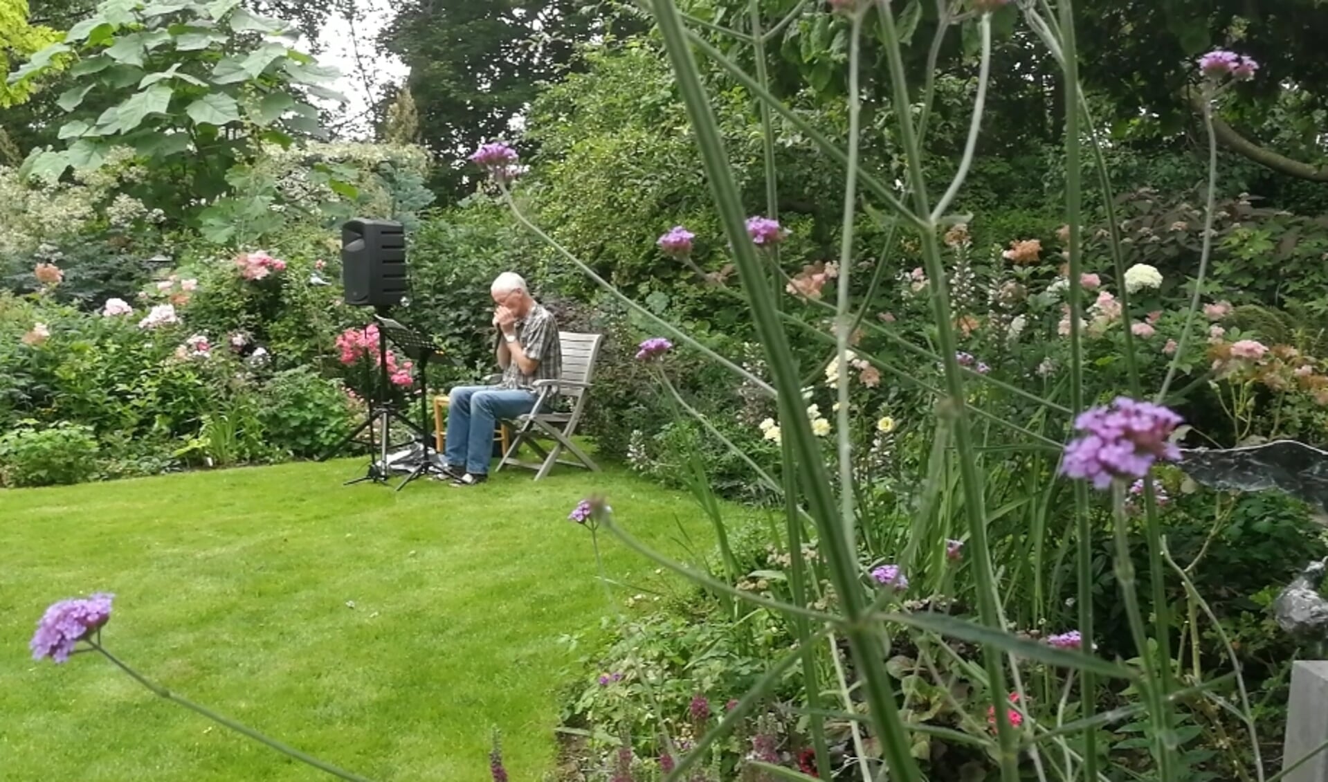 Koos Konijn zorgt voor sfeervolle muziek met zijn mondharmonicas in de tuin.