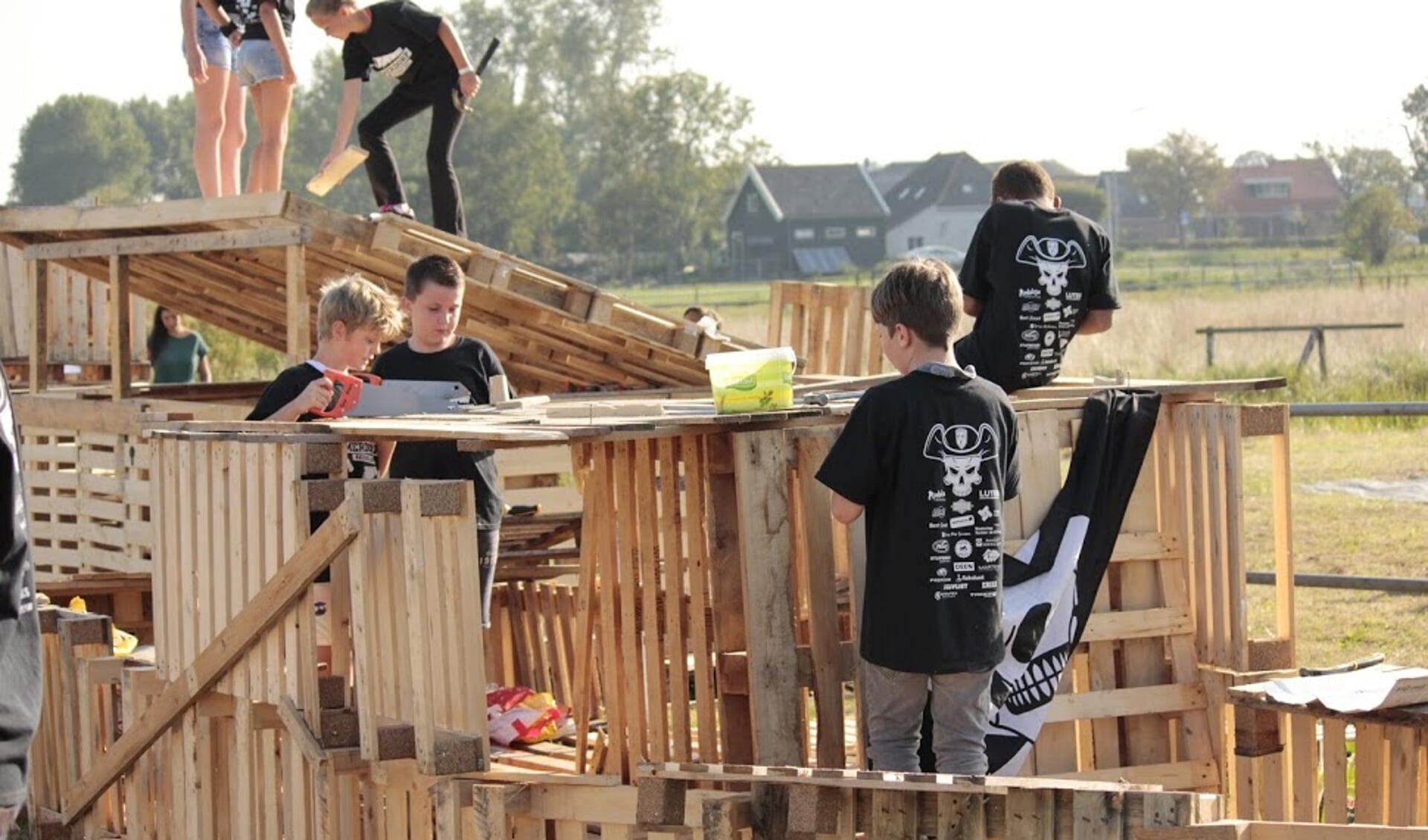 Jongeren zijn druk bezig met het bouwen van een dorp van pallets.