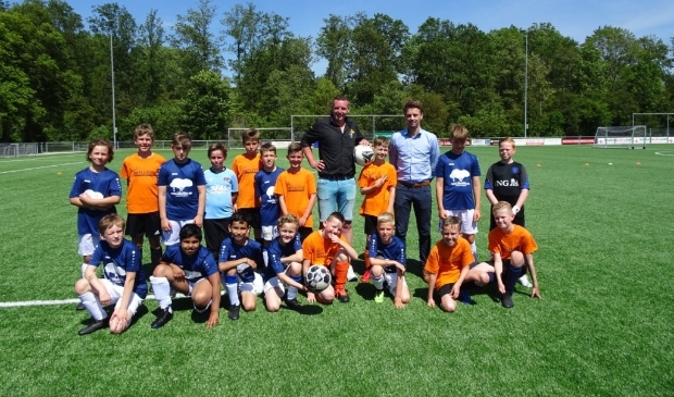 Sponsors René (l) en Marco met de teams van Reflector (in oranje shirts) en de Familieschool. Beide teams samen op de foto; ook dat zorgt voor verbinding. De Reflector won de wedstrijd overigens met 3-0.
