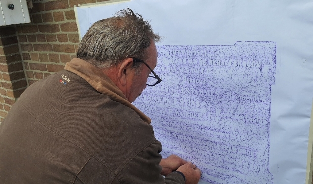 <p>Ed Oosterhuis brengt door ‘rubben’ de tekst van de gevelsteen over op papier. </p>
