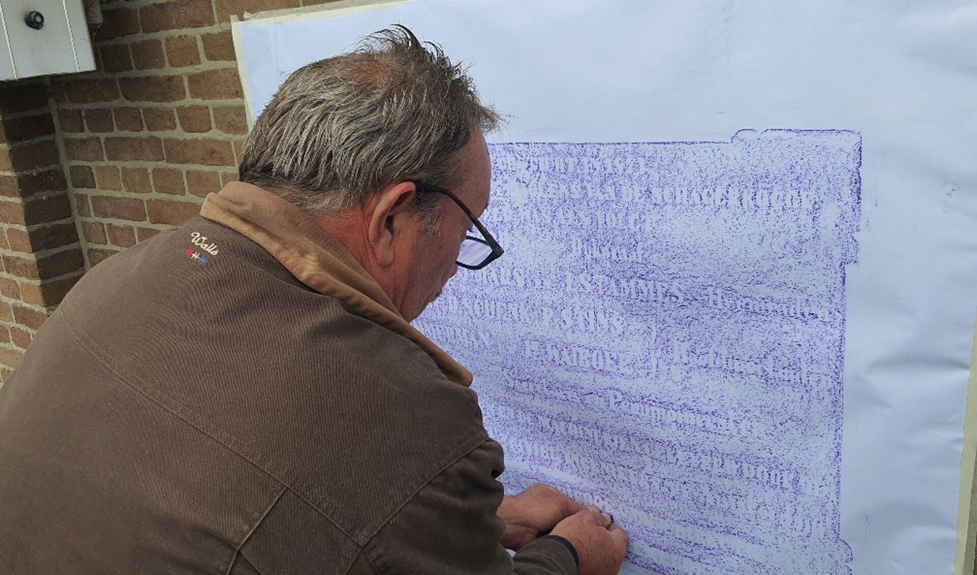 Ed Oosterhuis brengt door ‘rubben’ de tekst van de gevelsteen over op papier. 