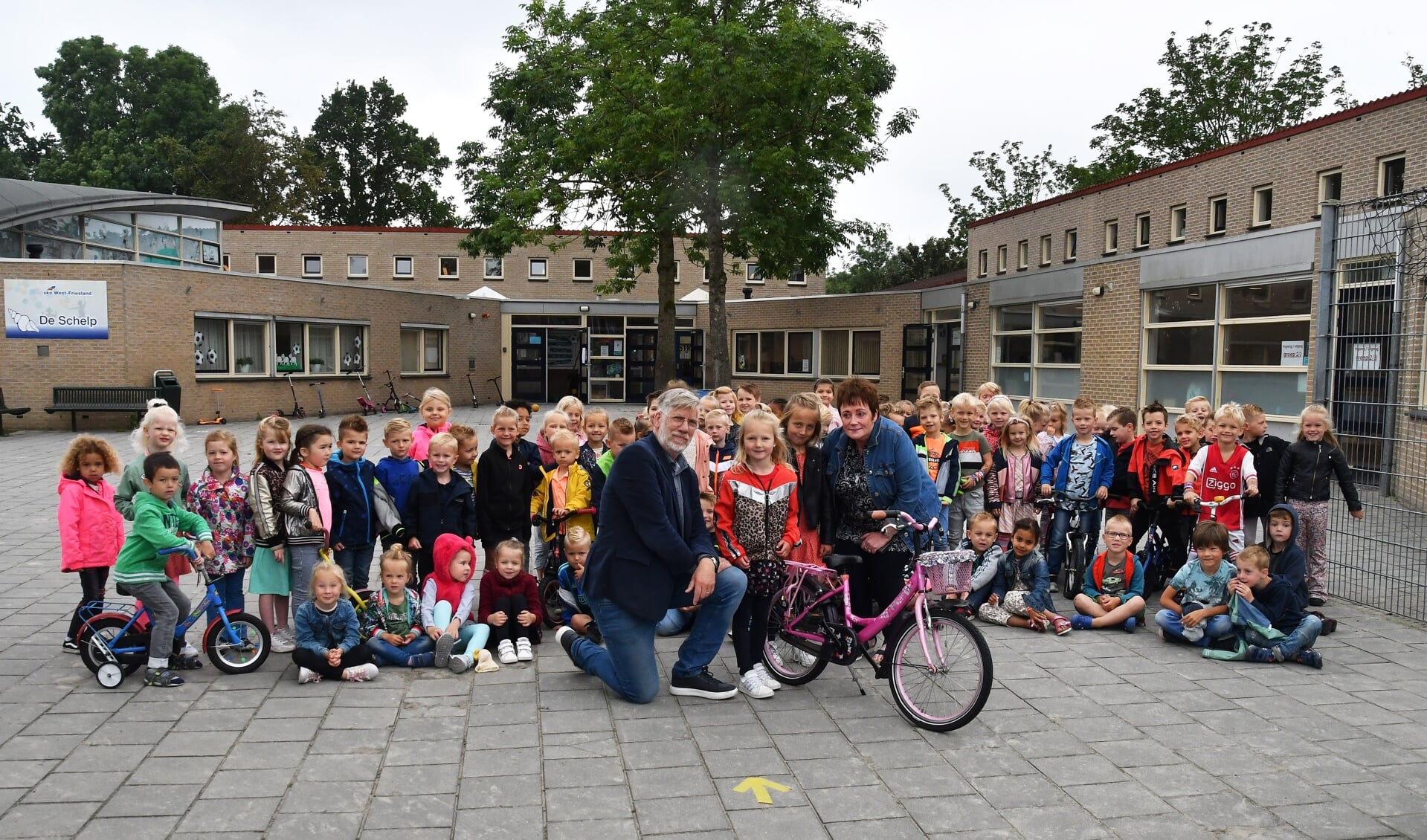 Geert Oosterhuis van Life Builders en Lida Kooijman van de actie 'Fietsjesvoorminima' kwamen naar De Schelp in Wervershoof om de kinderfietsjes van de kleuters in ontvangst te nemen.