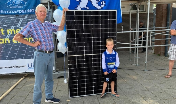 <p>Vrijwilliger Piet van Zijl en jeugdlid Javi Bruin flankeren één van de 197 zonnepanelen, die ADO’20 laat plaatsen door Patina Stroomdak.</p>