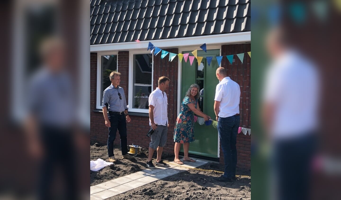 Levinus Jongmans van gemeente Zaanstad (links) en Jacob Prins van bouwbedrijf Van Der Gragt (rechts) begeleiden de trotse bewoners (midden) naar hun nieuwe, duurzame woning. 