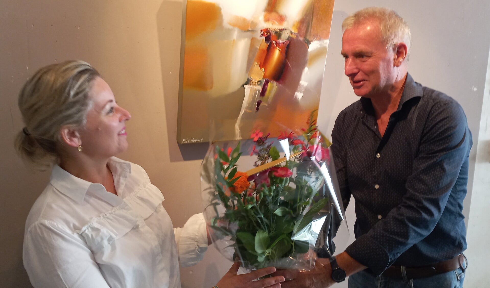 Mevrouw Verhey uit Zaltbommel krijgt bloemen van kunstschilder Arie Koning.